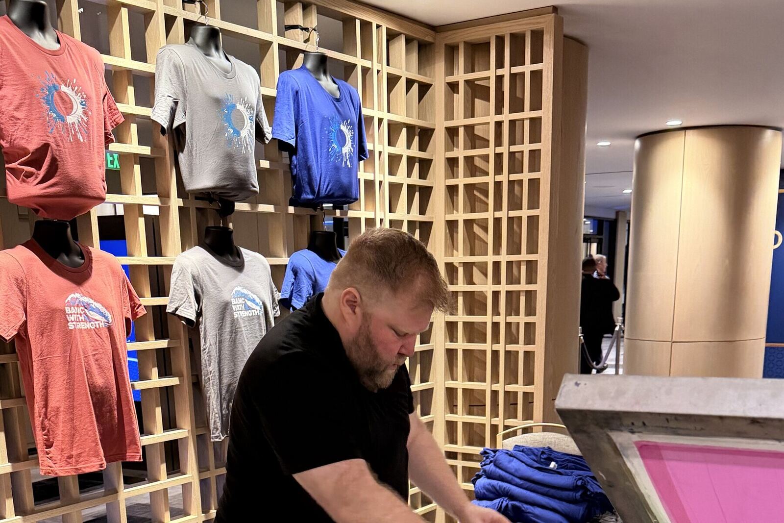 Pre-printed shirts folded on an event merch table next to a live bar
