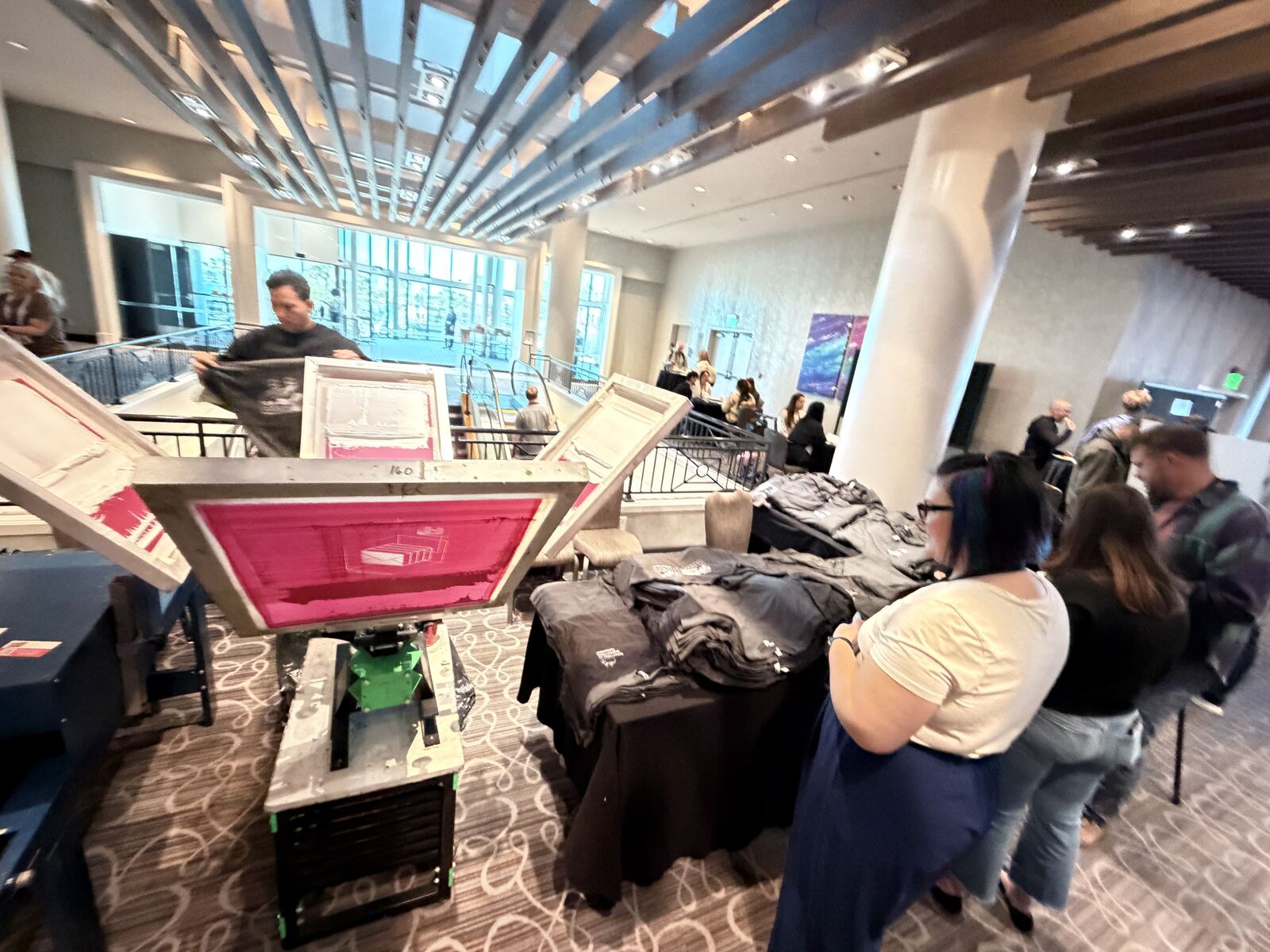 Heat press printing station with fresh printed t-shirts on display at an event booth